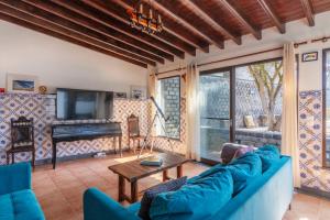 a living room with a blue couch and a television at Heated Saltwater Pool-Private Beachside Oasis in Mosteiros