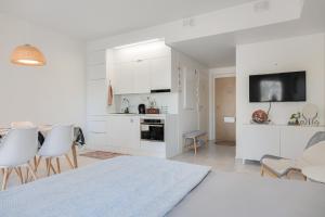 a white kitchen with white cabinets and a table and chairs at QnQ studio apartment in Helsinki