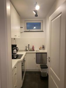 a small kitchen with white cabinets and a sink at Helle Souterrainwohnung mit Komfort in Munich