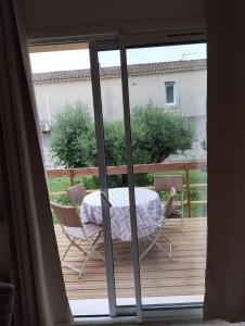 a sliding glass door with a table and chairs on a deck at Entre Terre et Camargue- Studio de Charme in Le Cailar