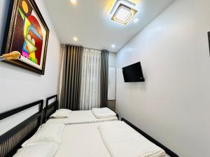 a bedroom with two beds and a painting on the wall at MUN HOMESTAY in Hue