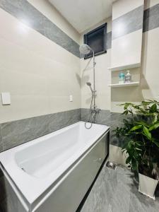 a white tub in a bathroom with a plant at MUN HOMESTAY in Hue +23 photos