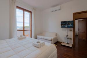 a white bedroom with a large bed and a couch at Villa Pia in Bevagna