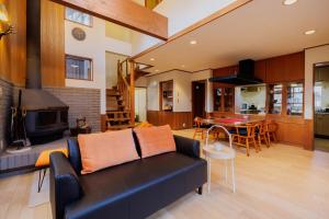 a living room with a black couch and a kitchen at 山水苑-道-温泉付き貸別荘ガイアリゾート in Zao
