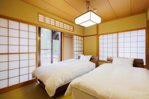 two beds in a room with yellow walls and windows at 山水苑-道-温泉付き貸別荘ガイアリゾート in Zao