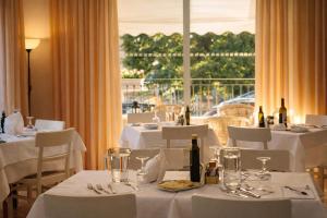 a restaurant with white tables and chairs and a window at Hotel Villa Gioiosa - Beach & Bistrot in Rimini +31 photos