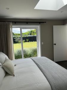 a bedroom with a large bed with a large window at Waihinau Cottage - One or Two Room Options! in Otaki
