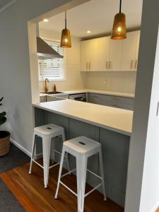 a kitchen with two stools and a large counter at Waihinau Cottage - One or Two Room Options! in Otaki
