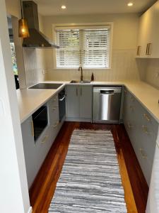 a kitchen with white cabinets and a rug on the floor at Waihinau Cottage - One or Two Room Options! in Otaki +1 photo
