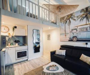 a living room with a black couch and a picture of a van at Le Van T2 Spacieux 44m2 wifi Clim in Valras-Plage