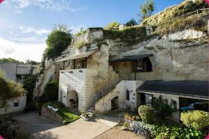 a stone house with a staircase in front of a mountain at Maison flanc de coteau in Turquant