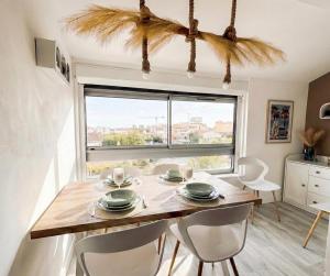 a dining room with a table and chairs and a window at Le Van T2 Spacieux 44m2 wifi Clim in Valras-Plage
