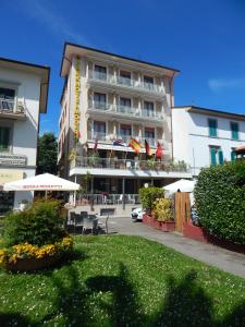 a hotel with tables and umbrellas in front of a building at Park Hotel in Montecatini Terme