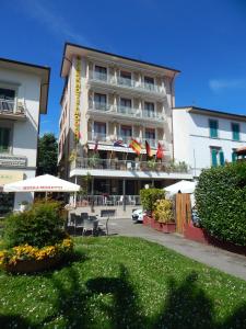 un hotel con mesas y sombrillas frente a un edificio en Park Hotel, en Montecatini Terme