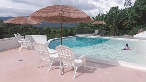 a little girl sitting in a swimming pool with an umbrella at Spacious & Scenic View with Swimming Pool Aza Sunset Villa 2 in Langkawi Intl