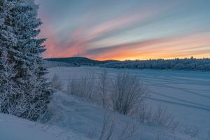 a snow covered field with a sunset in the background at Riverhouse Lumo in Ivalo