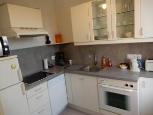 a kitchen with white cabinets and a sink at CAPRICES DE MER Appartement 1 A 2 PERS AVEC GRAND BALCON ET VUE PANORAMIQUE 300 M PLAGE LIT QUEEN SIZE PETIT DEJEUNER EN OPTION in Mers-les-Bains