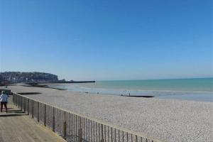 a person standing on a beach next to a fence at CAPRICES DE MER Appartement 1 A 2 PERS AVEC GRAND BALCON ET VUE PANORAMIQUE 300 M PLAGE LIT QUEEN SIZE PETIT DEJEUNER EN OPTION in Mers-les-Bains