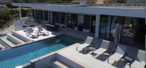 a house with a swimming pool and some chairs at VILLA IMPERIALE vue mer piscine in Pietrosella