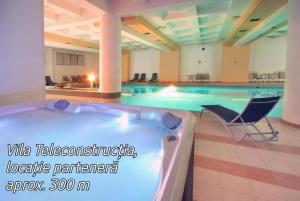 a large swimming pool with a tub and a chair at VILA DOBRU in Slănic-Moldova