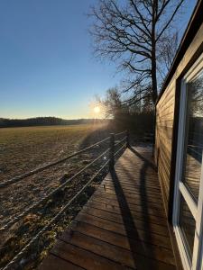 a wooden walkway next to a house and a field at Maringotka uprostřed divočiny in Proseč