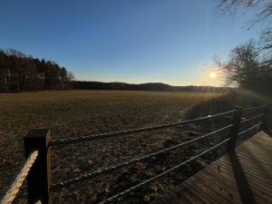 a fence in a field with the sun in the sky at Maringotka uprostřed divočiny in Proseč +4 photos