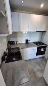 a small kitchen with white cabinets and a stove at Apartament WAGABUNDA in Wałbrzych +1 photo