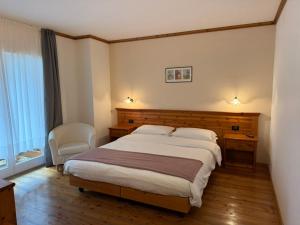 a hotel room with a bed and a chair at Hotel Garni Civetta in Selva di Cadore