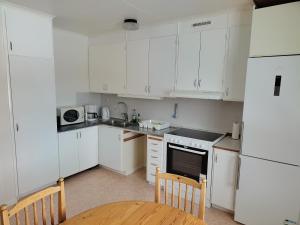 a kitchen with white cabinets and a table and chairs at Astrid40 in Bruzaholm