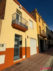 a yellow and orange building with a door and a balcony at El Mini Piso in San Juan de Moró