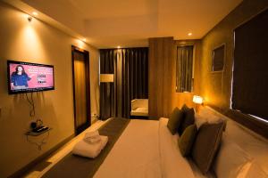 een hotelkamer met een bed en een tv aan de muur bij The Maureen in Calcutta