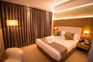 ein Hotelzimmer mit einem großen Bett und einem Fenster in der Unterkunft The Maureen in Kalkutta