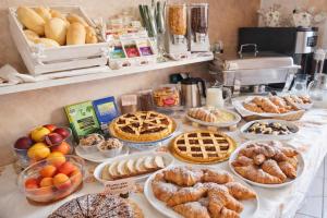 a table with various pastries and pies and other foods at Hotel Villa Gioiosa - Beach & Bistrot in Rimini