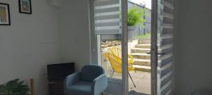 a living room with a chair and a sliding glass door at Studio cosy in Écouflant
