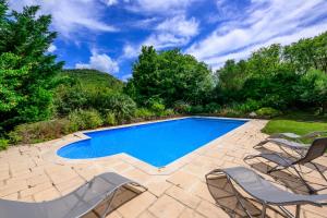 a swimming pool in a yard with chairs around it at La Bastide de Sigalas in Pompignan