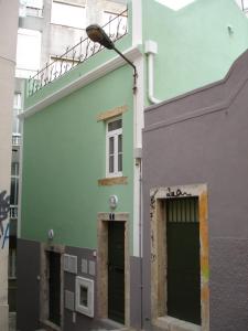 un bâtiment vert et gris avec une porte et un feu de rue dans l'établissement Apartamento Sapato, à Lisbonne