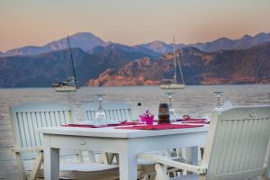 a white table with chairs and a table with wine glasses at Losta Sahil Evi 2 in Selimiye