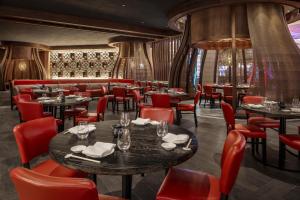 a dining room with tables and red chairs at Nobu Hotel New Orleans - A Caesars Rewards Destination in New Orleans