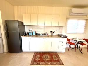 a kitchen with white cabinets and a black refrigerator at Cabin 168 in Neot Golan +12 photos