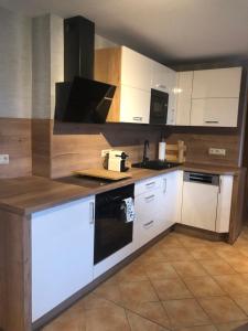a kitchen with white cabinets and a black appliance at Ferienwohnung Am Eichenberg in Blankenburg +19 photos