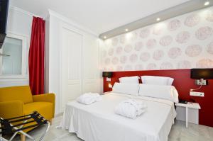 ein Schlafzimmer mit einem großen weißen Bett und einem gelben Stuhl in der Unterkunft The Zentral Arenal Suites in Sevilla