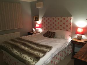 a bedroom with a large bed with a red headboard at Yew Tree Cottage in Maidford
