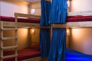 three bunk beds in a room with blue curtains at Dream Hostel Zaporizhia in Zaporozhye