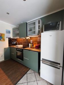 a kitchen with green cabinets and a white refrigerator at Forest house with outdoor hot tub in Jūrmala