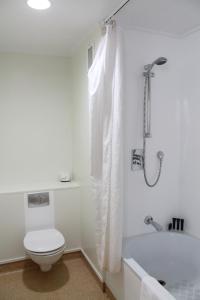 a white bathroom with a toilet and a bath tub at Willis Wellington Hotel in Wellington