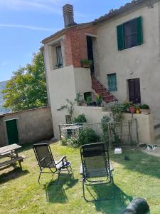 a house with two lawn chairs in front of it at Magrignano in Montieri