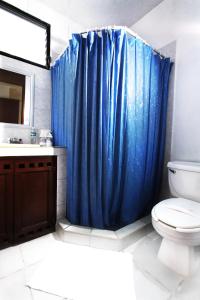 a blue shower curtain in a bathroom with a toilet at Hotel Los Girasoles in Cancún