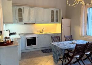 a kitchen with white cabinets and a table with chairs at Alkyonis House in Platithriás