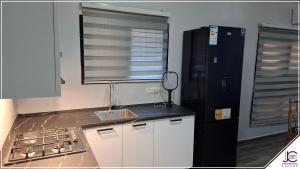 Eine Küche mit weißen Schränken, einer Spüle und einem schwarzen Kühlschrank in der Unterkunft La toure in M'bour + 4 Fotos