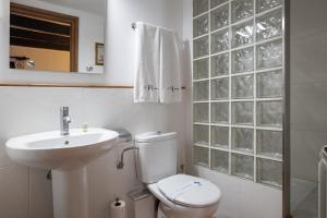 a white bathroom with a toilet and a sink at Apartaments Can Lo in Rupit +48 photos